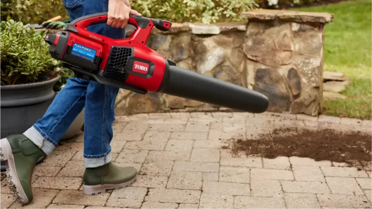 someone using a leaf blower to blow potting soil off a paver patio